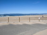 a paved beach with a fence in front of it and the ocean in the distance