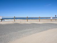 a paved beach with a fence in front of it and the ocean in the distance