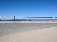 a paved beach with a fence in front of it and the ocean in the distance