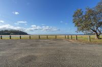 parking lot with grass and trees beside the water in the distance is a tree on a sandy bank