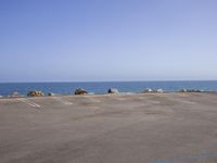 a parking lot with parked vehicles and the ocean in the back ground, on an otherwise empty lot