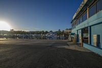 the sun is peeking through the window of a small store in a parking lot with several parked vehicles