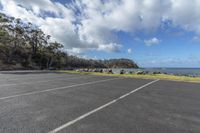 the empty parking lot is situated beside the beach by the water's edge, with boats