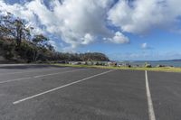 a parking lot with an ocean in the background and trees around it on a clear day