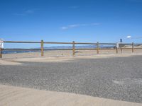 a paved beach with a fence in front of it and the ocean in the distance