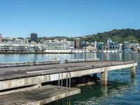 a body of water with a pier in the foreground, and buildings in the background