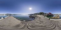 a dock sitting next to a body of water under a bright blue sky with an island