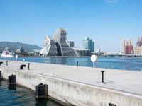 some dock and water and some buildings with people in it in the background and mountains