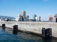 some dock and water and some buildings with people in it in the background and mountains