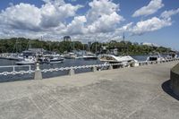 boat dock with boats docked on water and a group of people on a ramp under a cloudy sky