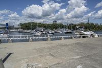 boat dock with boats docked on water and a group of people on a ramp under a cloudy sky