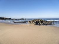 the sand and blue ocean are very calm on this beach as the water comes up from the rocks