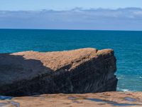 a person stands on rocks in the water while the ocean looks out to the horizon