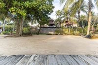 an image of a small resort setting with trees and houses in the background, overlooking the beach,