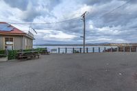 a bench with solar panels sitting in front of a building with a view of the water and houses in the background