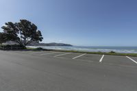 an empty parking lot in front of the beach and mountains under blue skies - - and the ocean