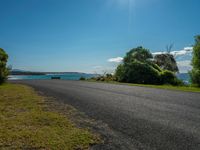 empty roadway by the beach with green grass and trees near by on hill at top