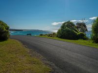 empty roadway by the beach with green grass and trees near by on hill at top