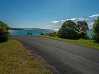 empty roadway by the beach with green grass and trees near by on hill at top