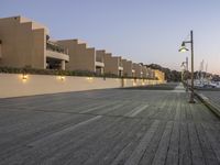 the boardwalk between two buildings is empty on a clear day as the sun sets in