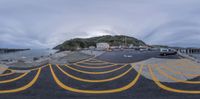 a fisheye fish - eye picture shows the street and beach from an angle with a bridge in the background