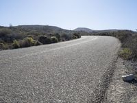 a rock and gravel road next to a large hill in the distance is a mountainous landscape and a mountain