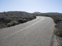 a rock and gravel road next to a large hill in the distance is a mountainous landscape and a mountain