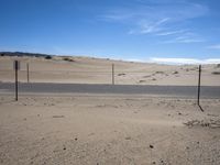 a paved beach with a fence in front of it and the ocean in the distance