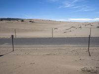 a paved beach with a fence in front of it and the ocean in the distance