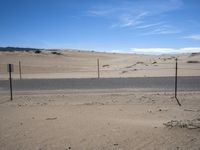 a paved beach with a fence in front of it and the ocean in the distance