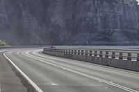 a long highway that has a boat coming up it's side with mountains in the background