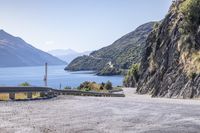 a curve of road with a small lighthouse at the top of it next to mountains