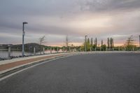 a bike rack on the street by a river bank at sunset with a parking lot