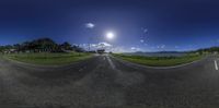 view of a road and road in front of a body of water and the sun