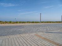 two people standing on the brick ground playing with a kite in the distance on an oceanfront