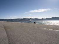 two people on a shore line flying kites next to the ocean in spain and europe