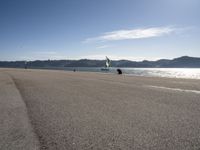 two people on a shore line flying kites next to the ocean in spain and europe