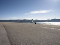 two people on a shore line flying kites next to the ocean in spain and europe