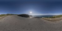 this is a fish eye lens of a road near the ocean in france, with a sun shining behind the road