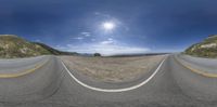 a 360 - turn photo of a road with hills in the background and bright clouds