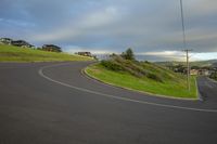 road curves down the side of the hill with houses in the distance and in front