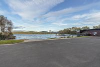 view of a house sitting on top of a lake by the water, and a dock to the right of the road