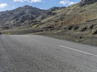 a small child is sitting on a motorcycle in the middle of a road next to some mountains