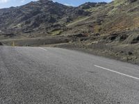 a small child is sitting on a motorcycle in the middle of a road next to some mountains