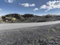 a motorcycle driving on the road on a sunny day in iceland, in a natural background, the hills and sky are dotted