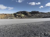 a motorcycle driving on the road on a sunny day in iceland, in a natural background, the hills and sky are dotted