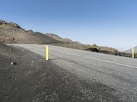 there is a bicycle on the side of a road that has been paved with a yellow pole