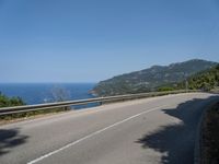 a motorcycle riding along the side of a scenic road near the ocean on a clear day