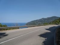 a motorcycle riding along the side of a scenic road near the ocean on a clear day