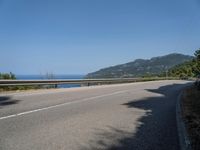 a motorcycle riding along the side of a scenic road near the ocean on a clear day